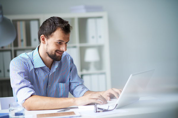 Happy bearded man using his laptop.